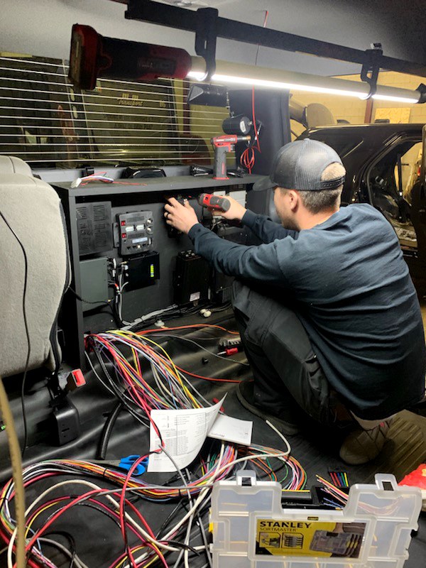 A GenComm employee wiring an emergency service vehicle