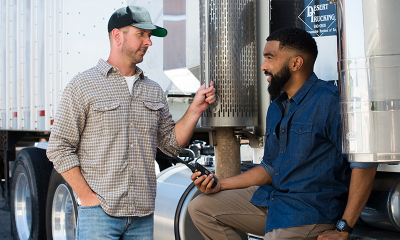 A trucker holding GenComm radio while having a conversation