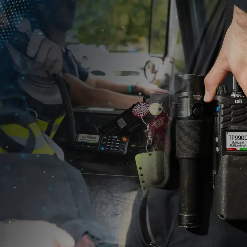 Tait 9900 mobile radio and a first responder holding it while it is on their belt